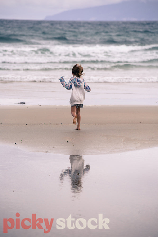 Happy and joyful child running towards the moana, sea at Tawharanui beach