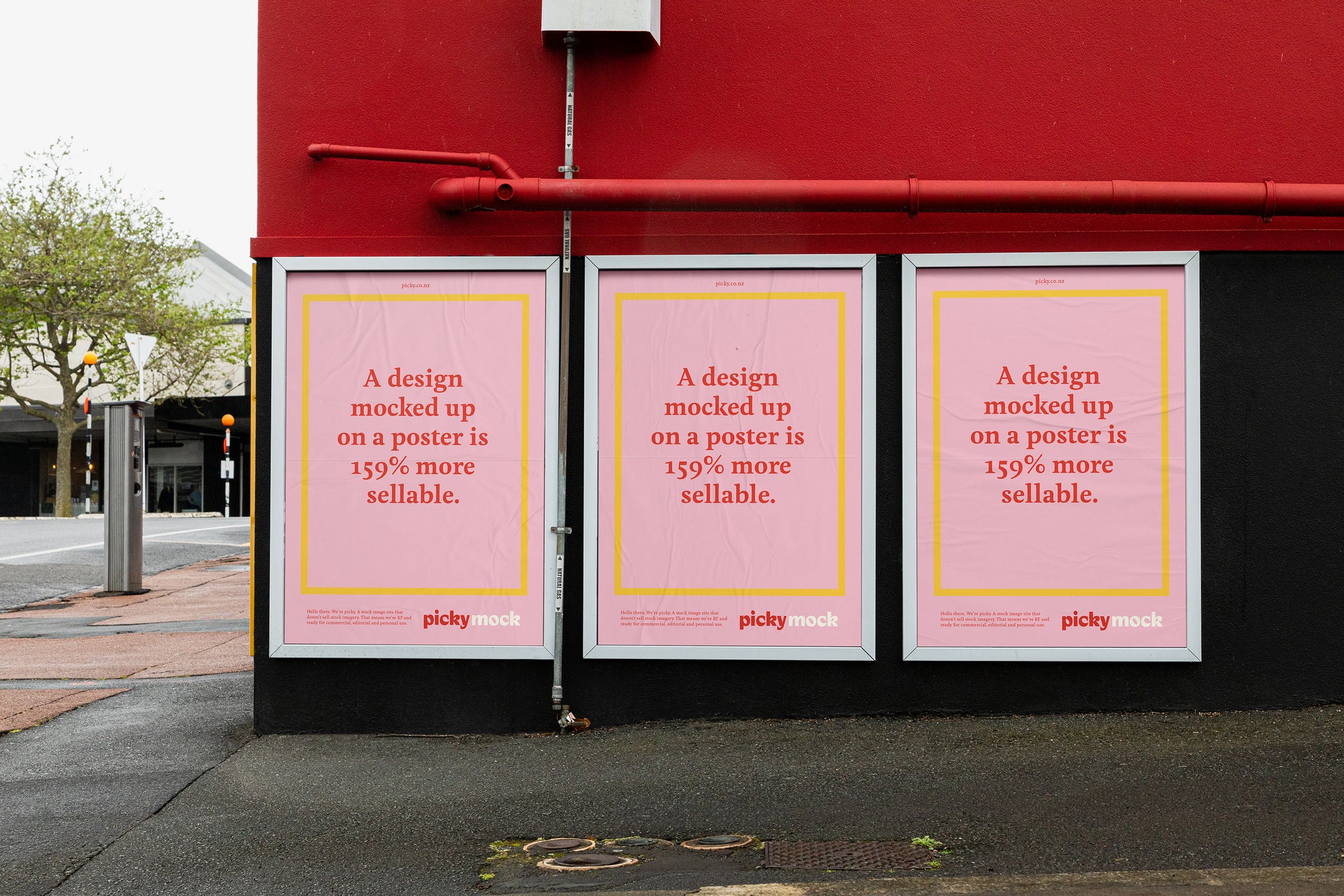 Three street posters sit in white frames, against a red and black wall.