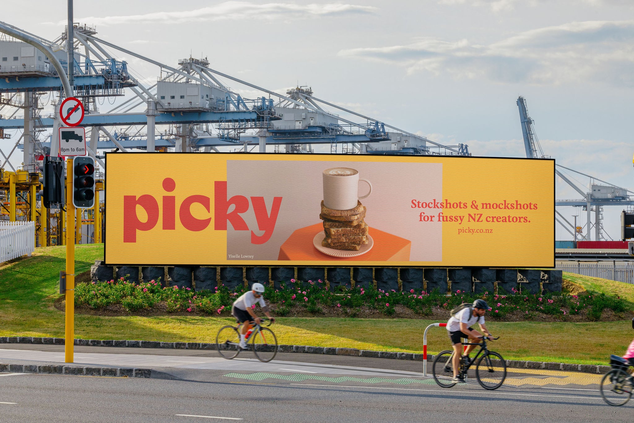 Digital billboard in Auckland Downtown, against the port. Bikes whizzing by. Port of Auckland in background. 