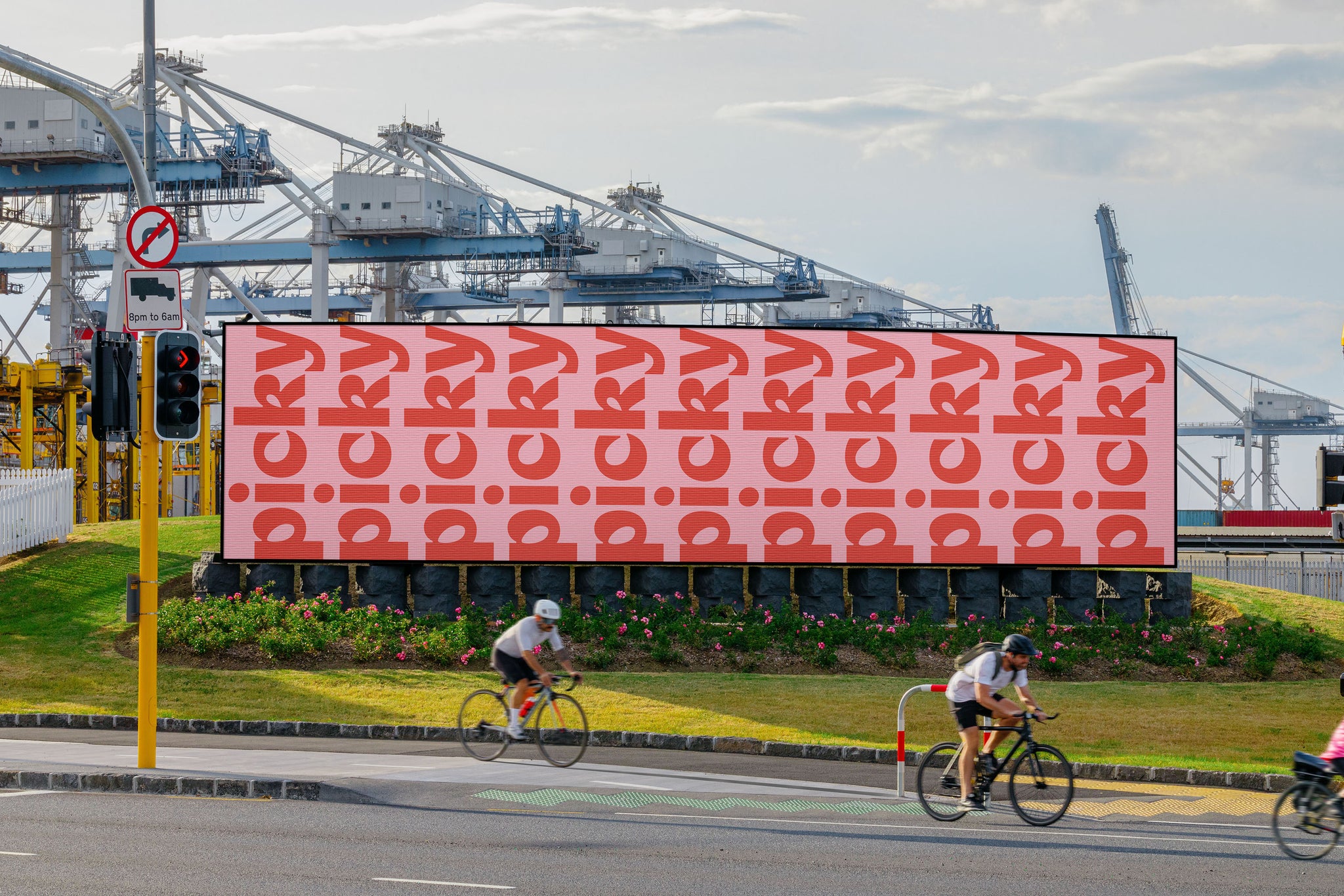 Digital billboard in Auckland Downtown, against the port. Bikes whizzing by. Port of Auckland in background. 