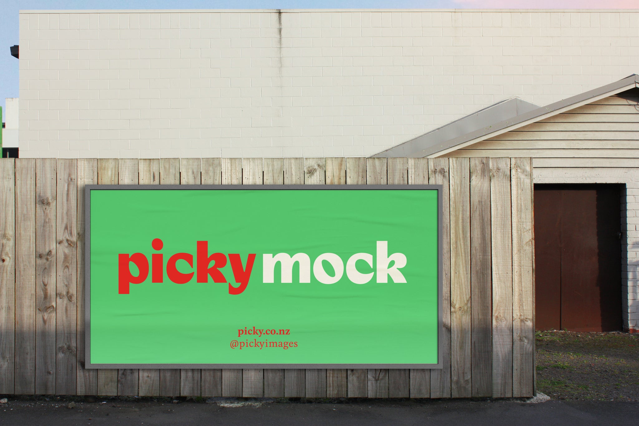 A mockup image of a six metre by three metre billboard sitting on a residential wooden fence. The house is single story and can just be seen beyond and to the right of the fence. There is a placeholder image on the billboard, complete with Picky images branding.