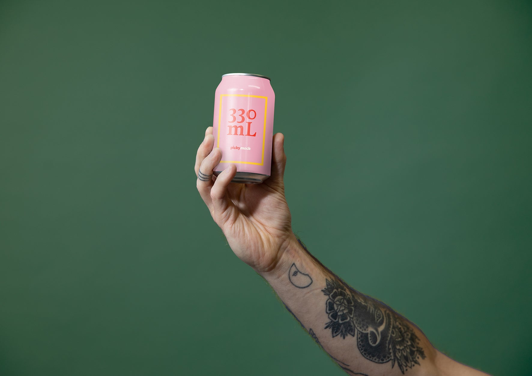 Drinks can held up against studio background by hand with tattoos.