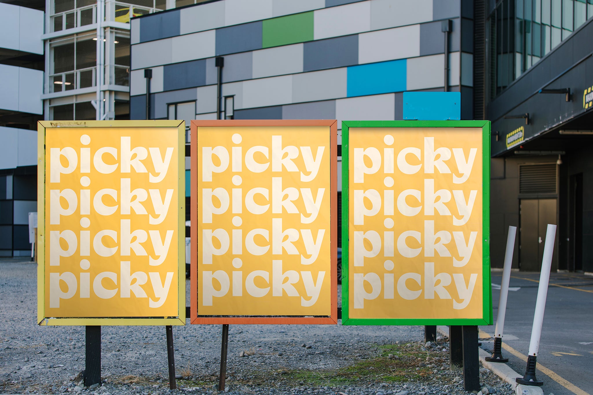 Series of three colourful street posters freestanding against colourful building.