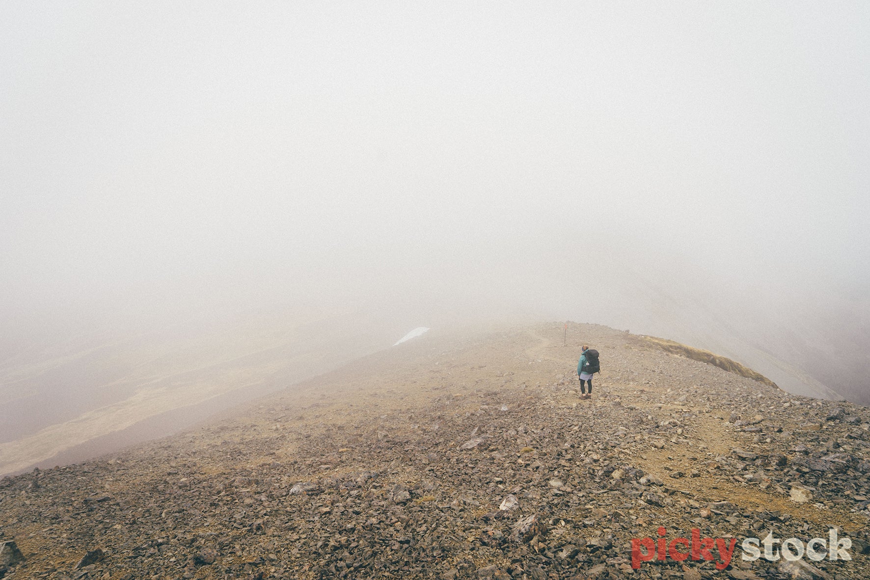 A hiker on a rocky ridge in the fog