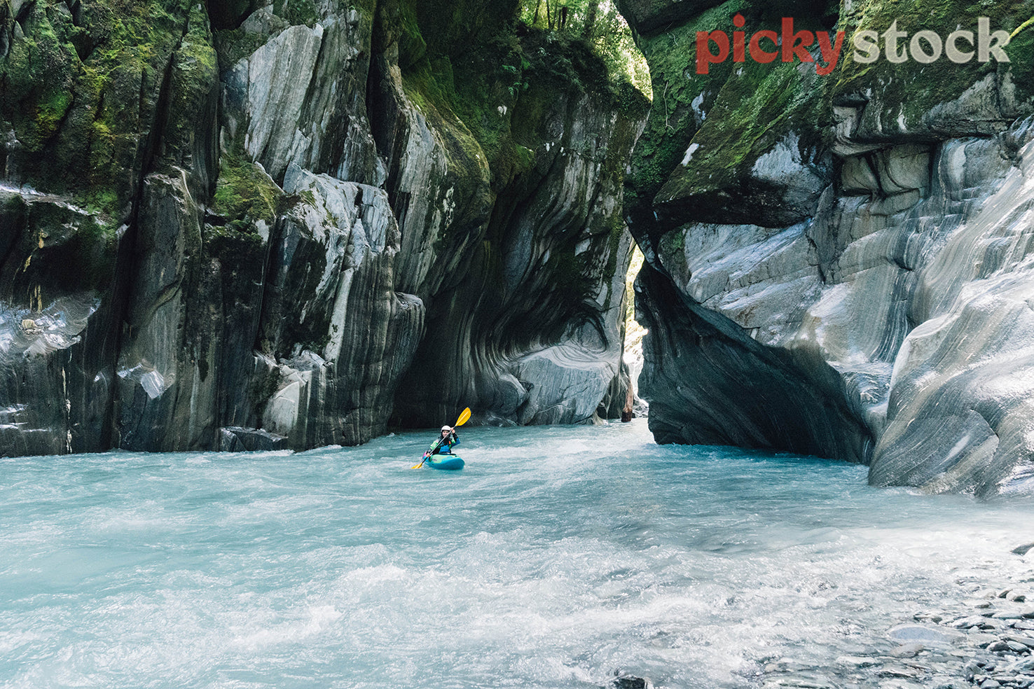Whitewater kayaker in a gorge on a turquoise river