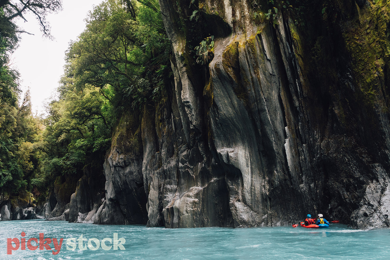 Whitewater kayakers enjoying a beautiful river gorge on a glacial river