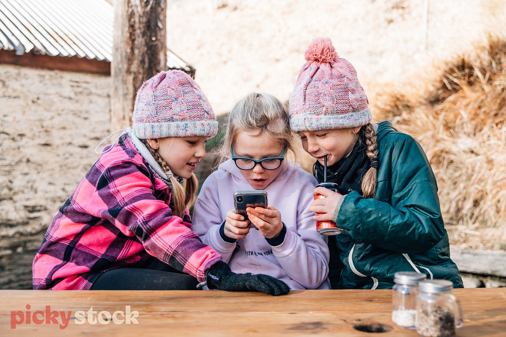 Three girls in Arrowtown, looking at a mobile device. New Zealand based stock image. 