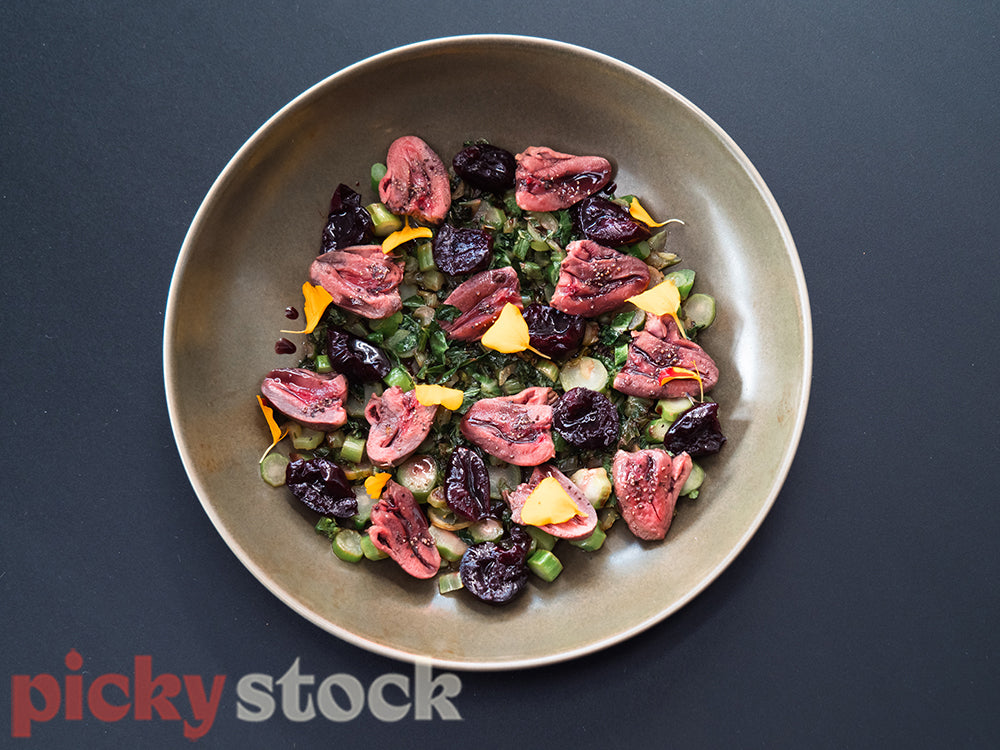 Duck hearts, cherries and vegetables dish from a top down view.
