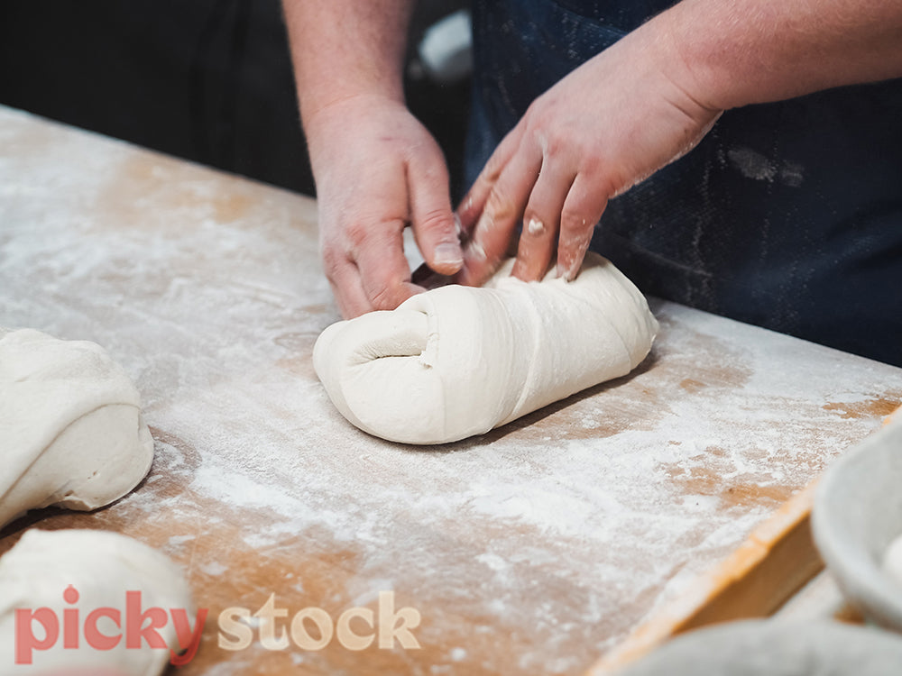 Baker shaping bread dough into loaves.