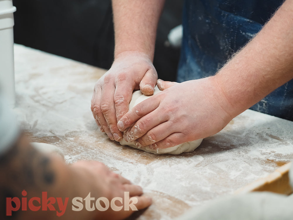 Baker shaping bread dough into loaves.