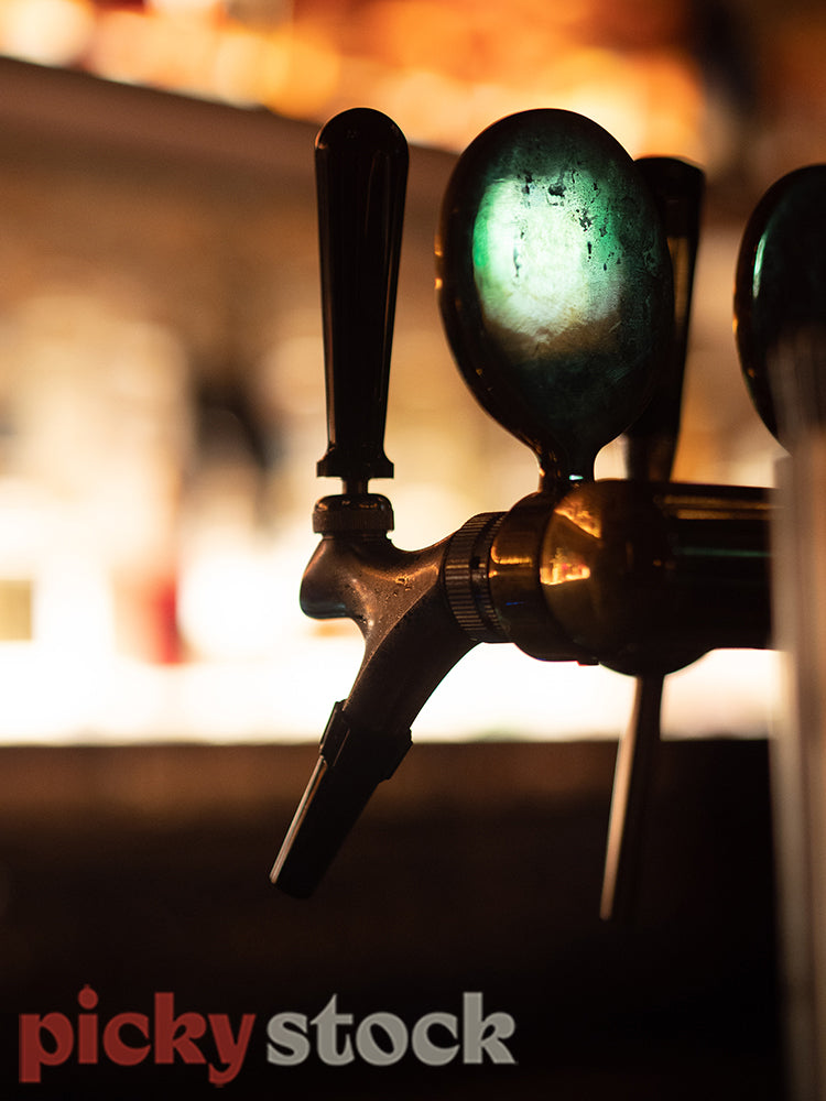 Moody picture of beer taps in a bar.