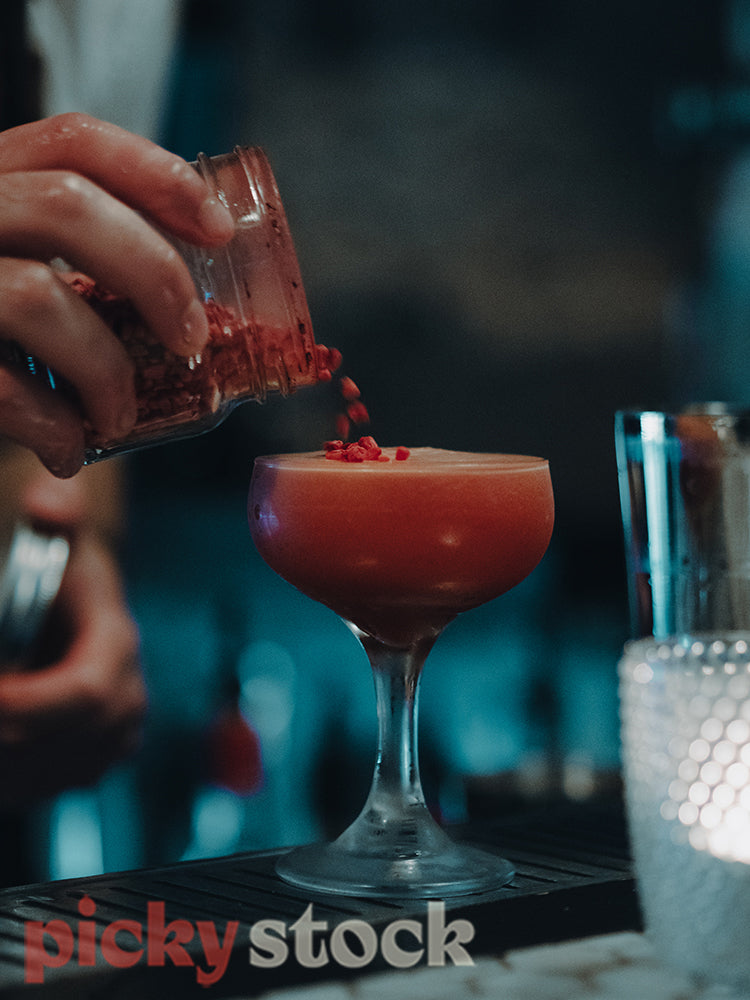 Barman garnishing a vodka, grenadine, raspberry and coffee cocktail.