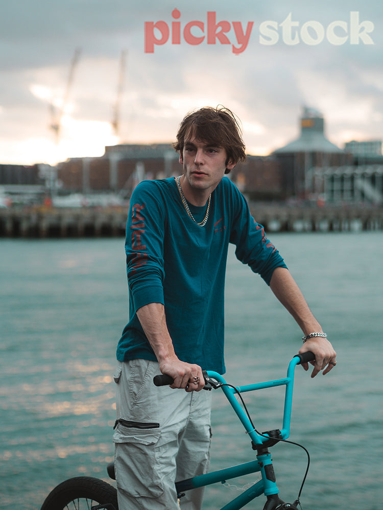 Young adult man riding a BMX by the sea. Taken on a warf by the harbour.