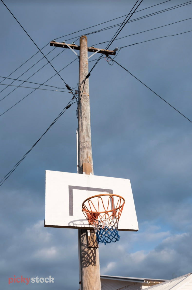 Looking up towards an inner city basketball hoop & backboard.