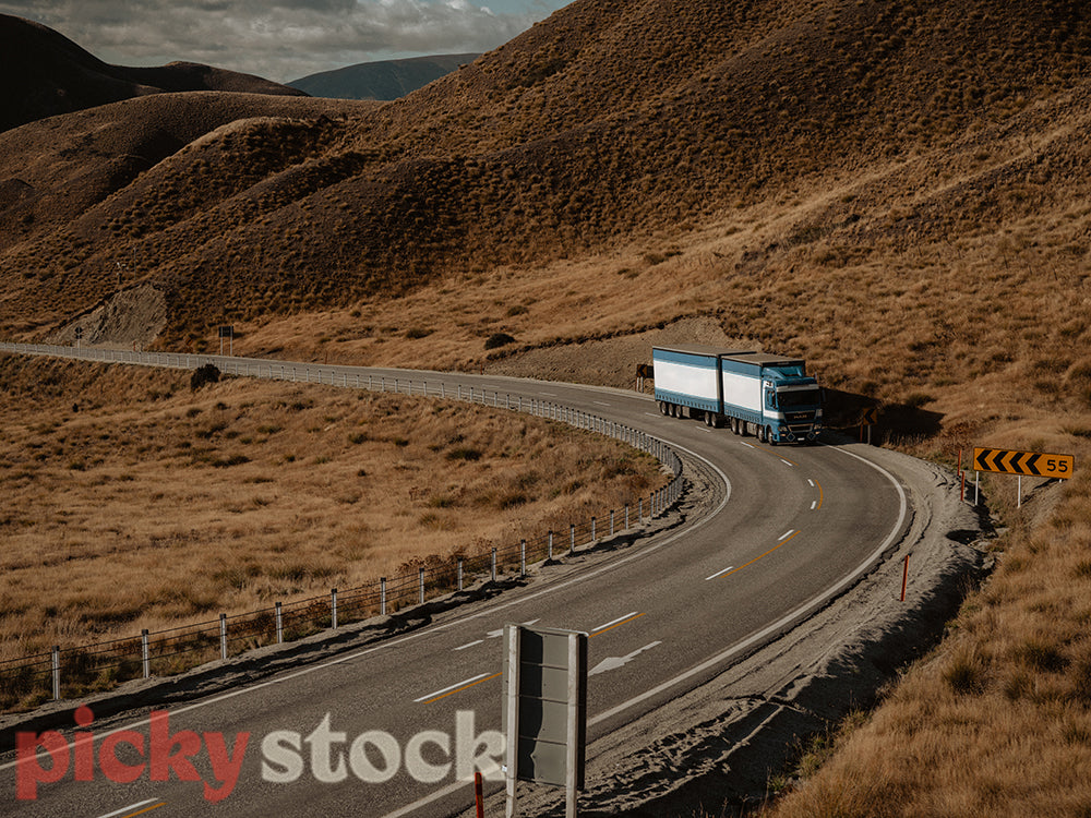 Truck driving through Lindis Pass in winter.