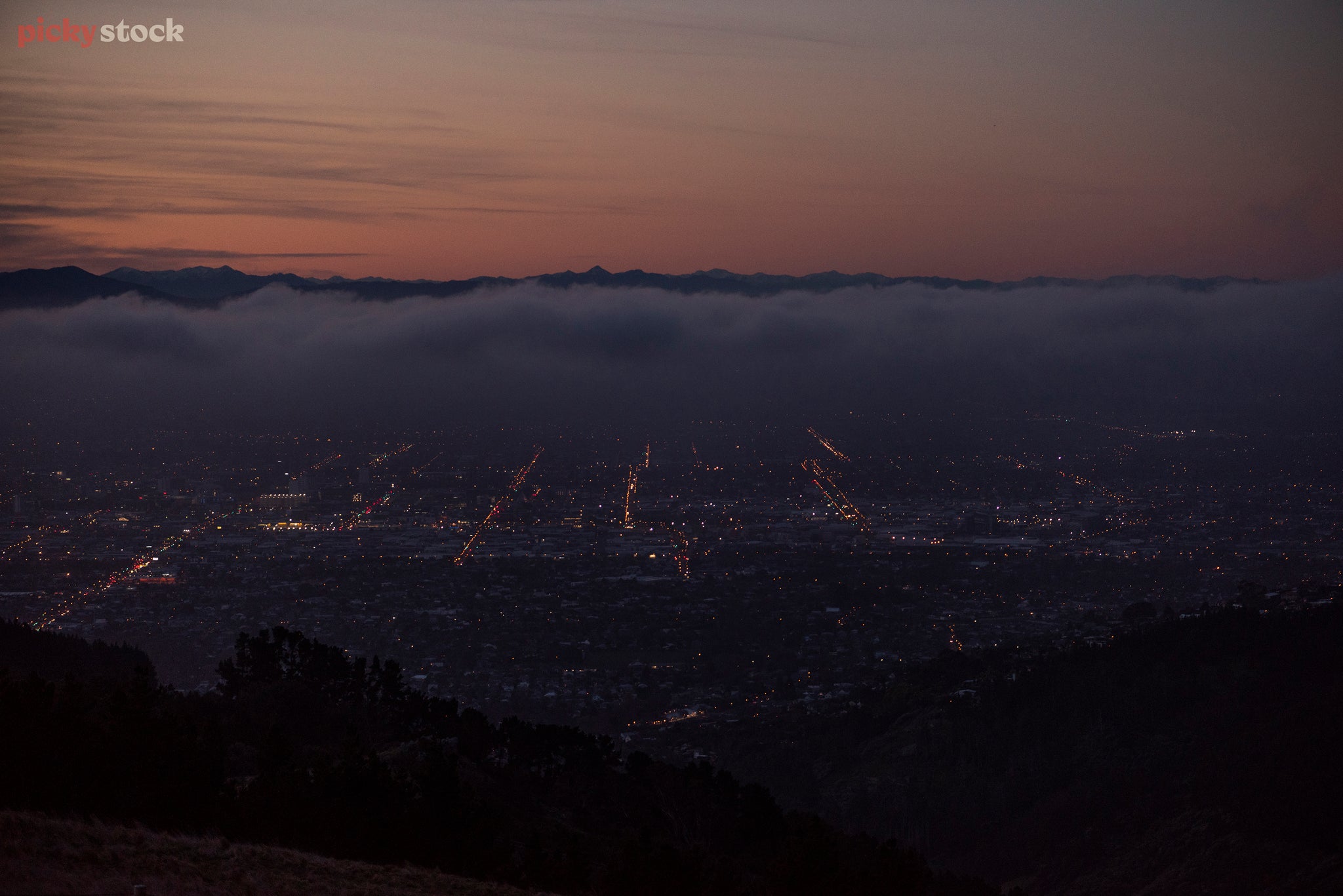 A very hazy and dark viewpoint from the Moody Port Hills overlooking Christchurch. In the far distance the purple and pink dark sunsetting just breaks up the night sky. 