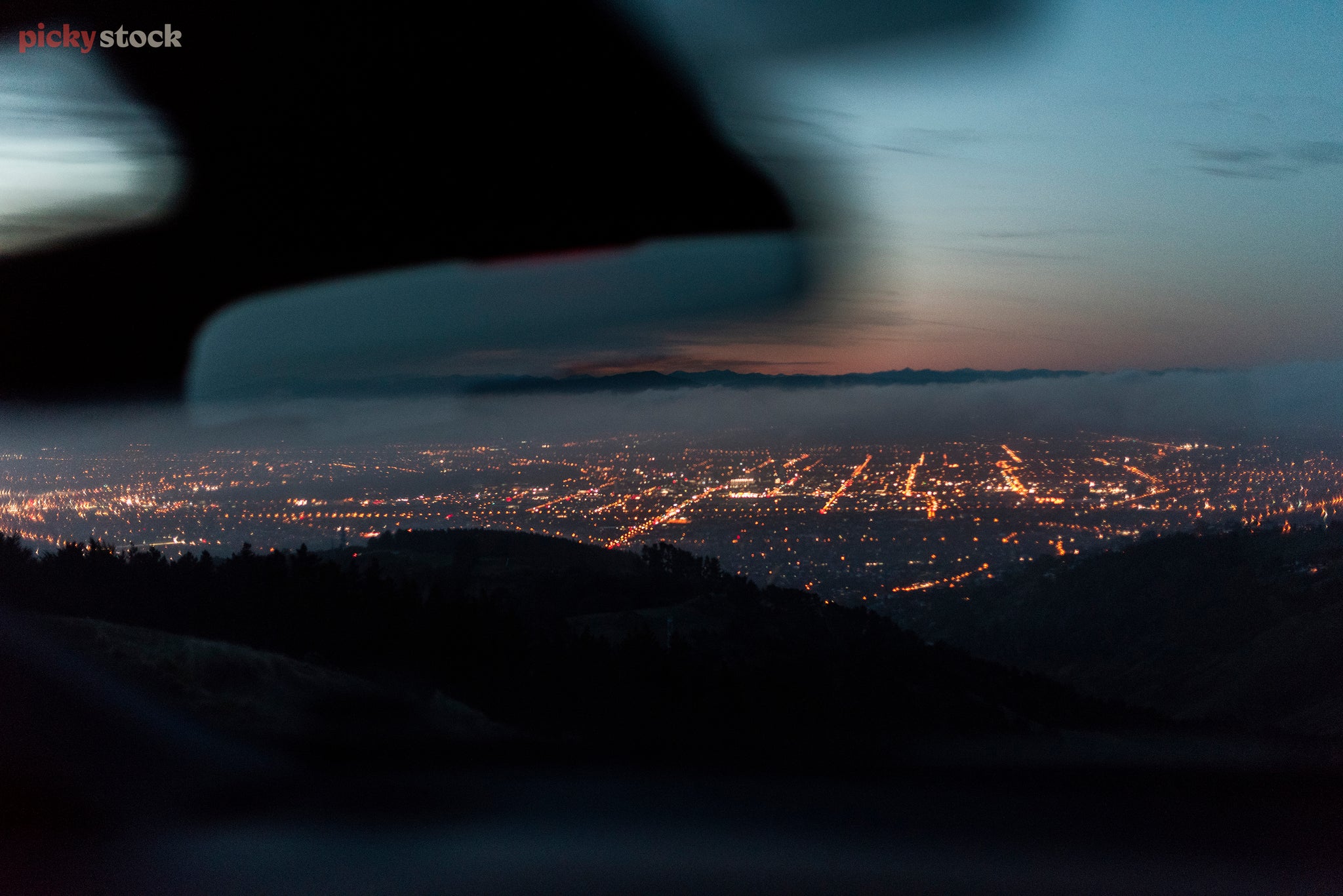 Shot from the front seat of a car of Christchurch on an early morning drive, the city lights shine through a fog.