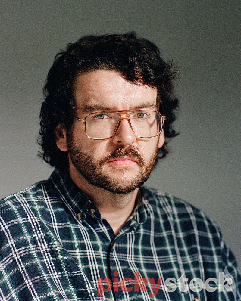 Gay man portrait on plain background, prominent glasses  