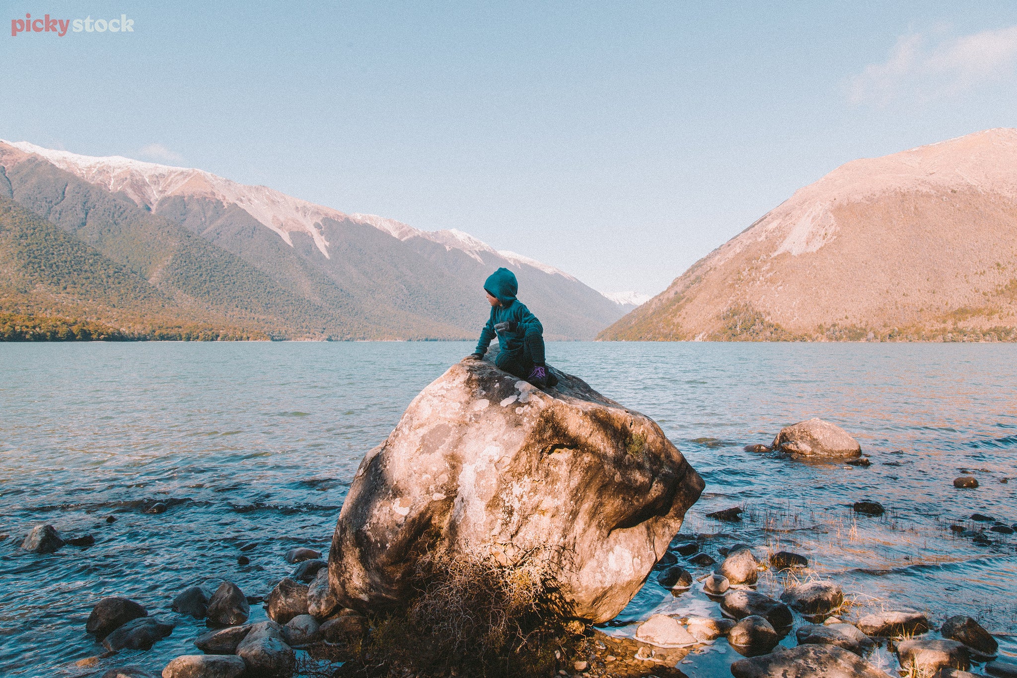 Boy sits on rock at Lake Rotoiti - landscape
