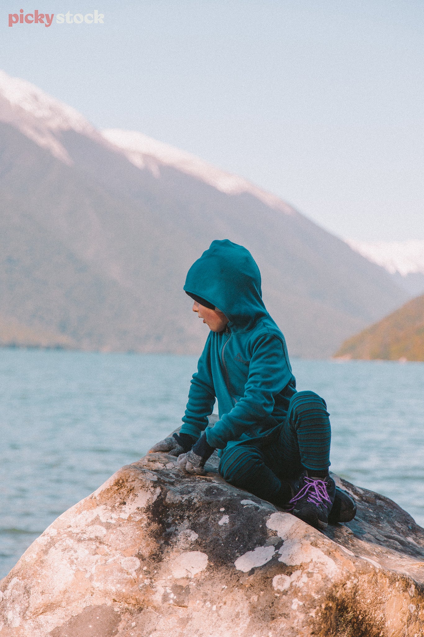 Boy sits on rock at Lake Rotoiti