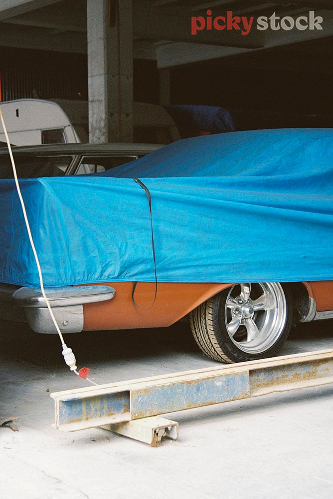 Retro car under the blue tarp in the garage. 