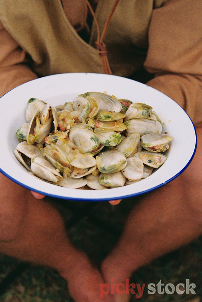 Holding out a fresh plate of pipis in a white bowl.