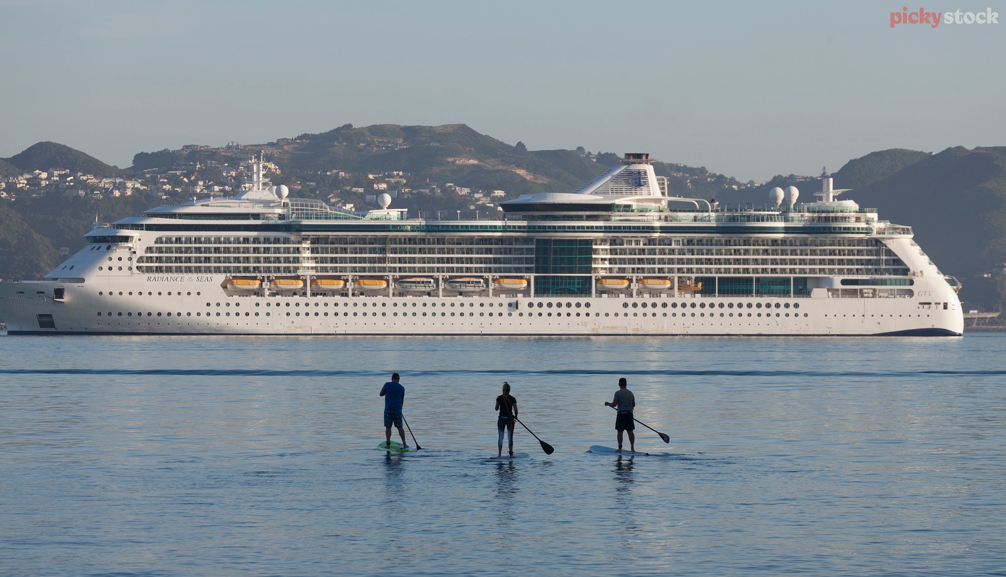 Three paddle boarders take in the cruise ship sites at Oriental Bay. Water is very blue. A clear Wellington day. 