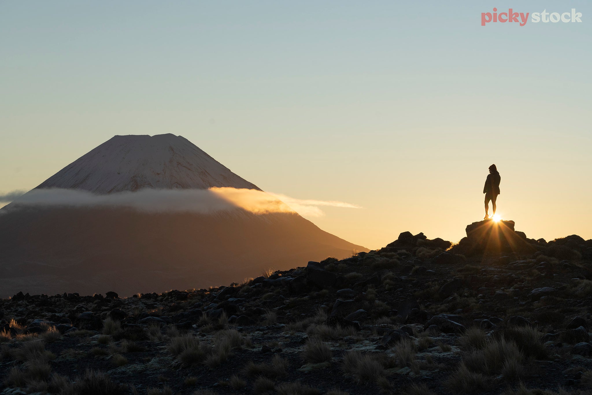 Solo framel tramper / hiker looking across at Mt Ngauruhoe from Mt Ruapehu at sunrise. 