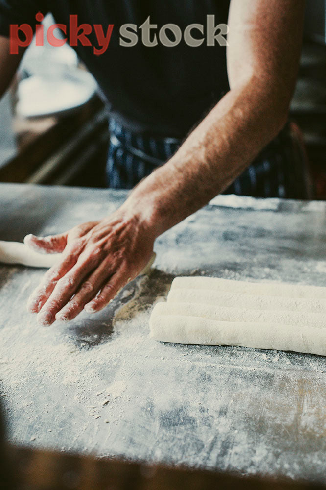 Chef with floury hands rolling gnocchi dough.