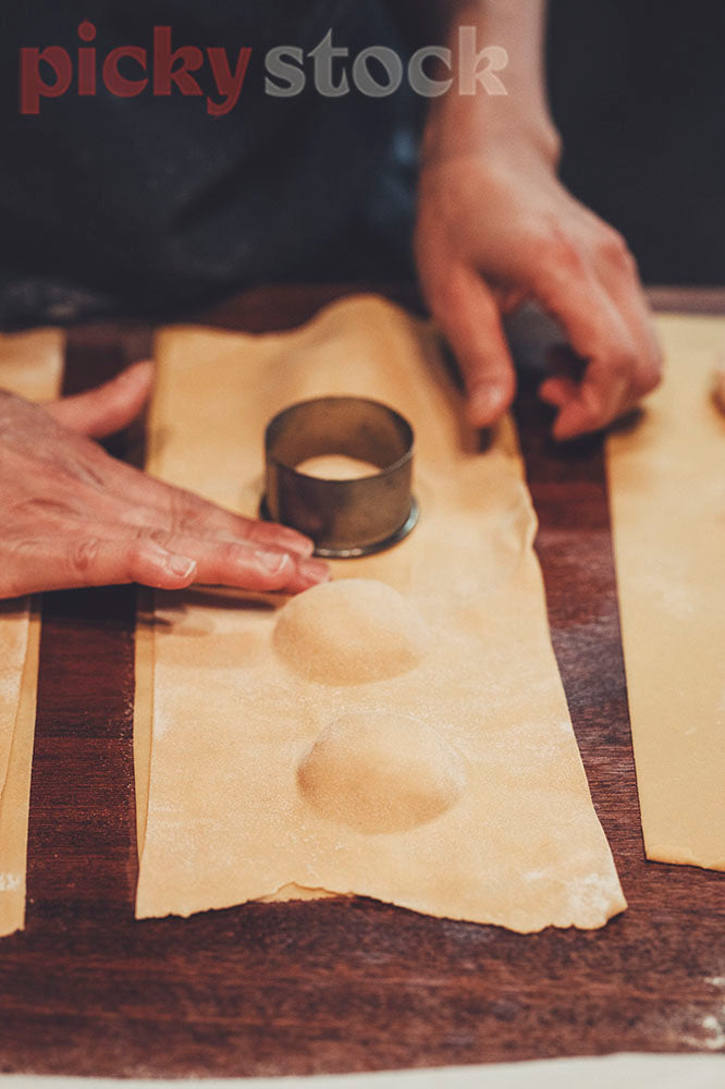 Chef uses hands to press down the sides of pasta sheets.