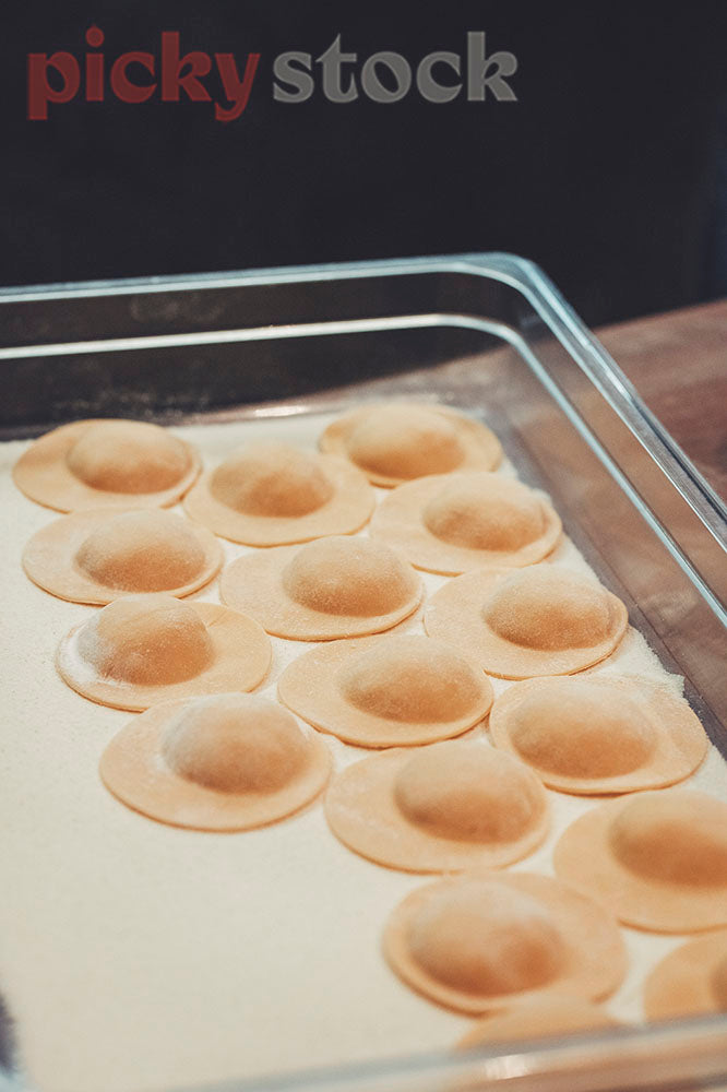 Freshly shaped ravioli parcels sit ready to cook.