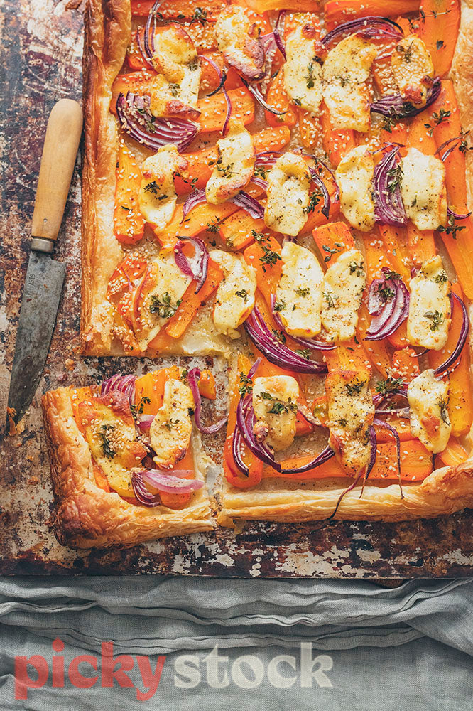 Roasted baby carrot and red onion tart with haloumi, with one piece sliced out. 
