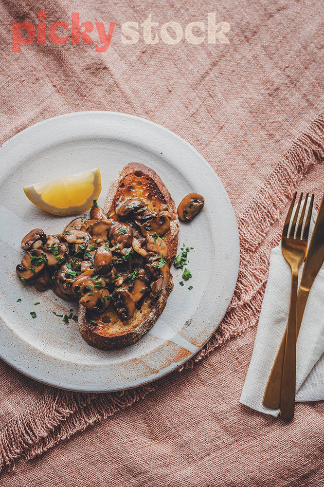 Classic creamy mushrooms on sourdough toast, plated up on a pink linen tablecloth. 