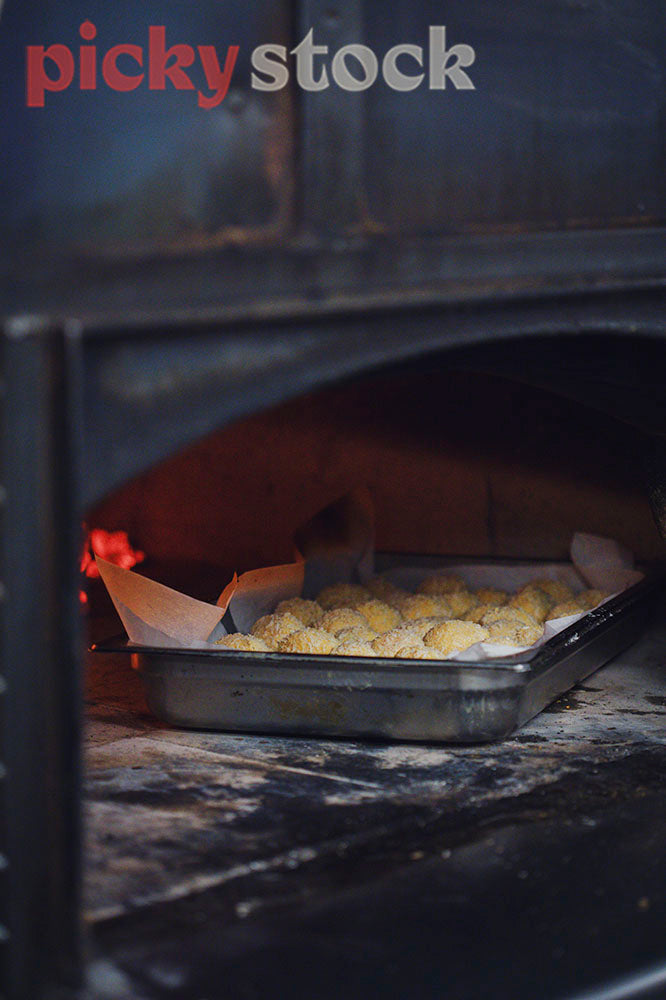 Tray of risotto balls cooking in tray inside wood fired oven