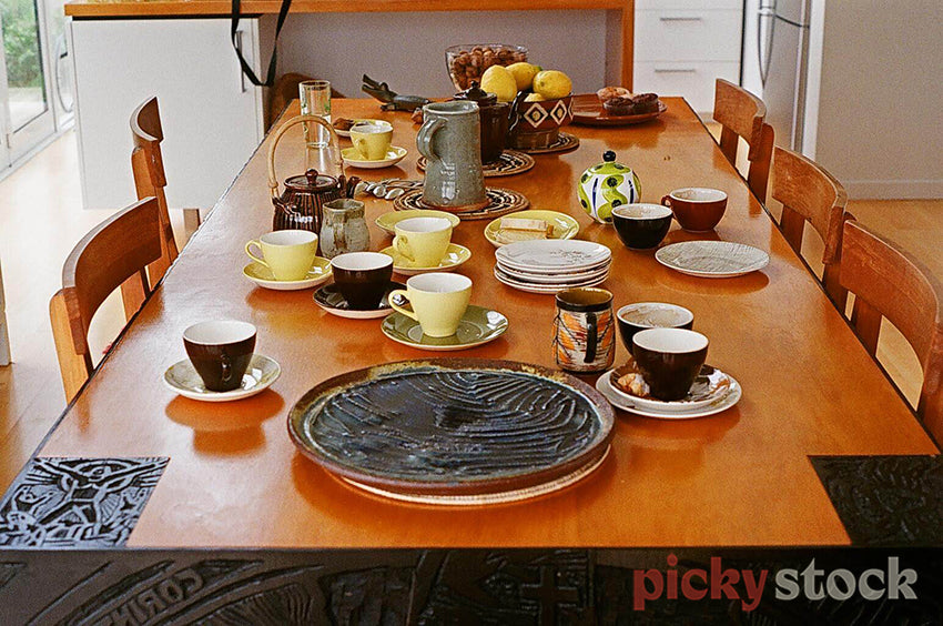Ceramics  laid out on wooden dining room table in the house of an artist.