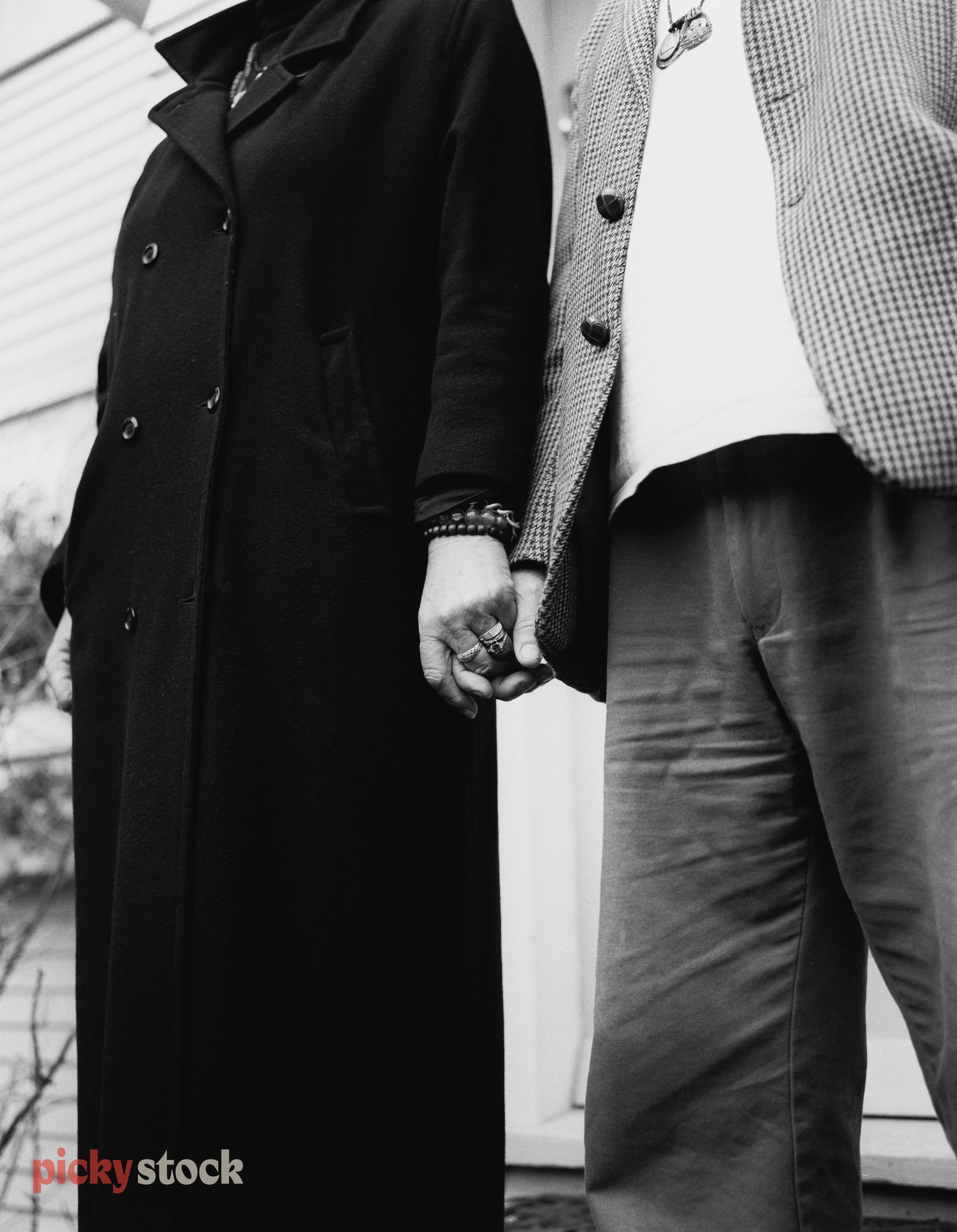 Black and white photograph of couple holding hands, they grip each other. 