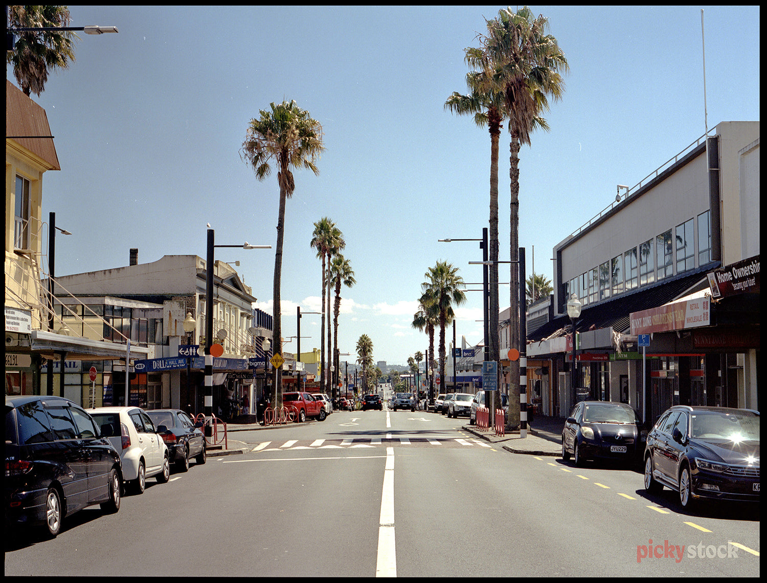 Down the mainstream of Otahuhu main street with palm trees in the distance. 