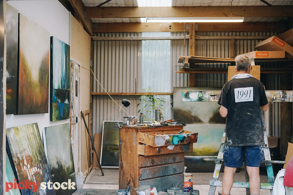 Painter in his art studio surrounded by his artwork 