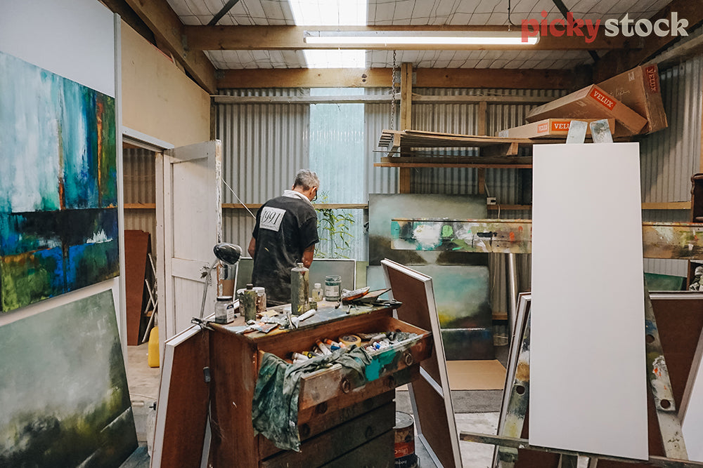 Painter in his art studio surrounded by his artwork 