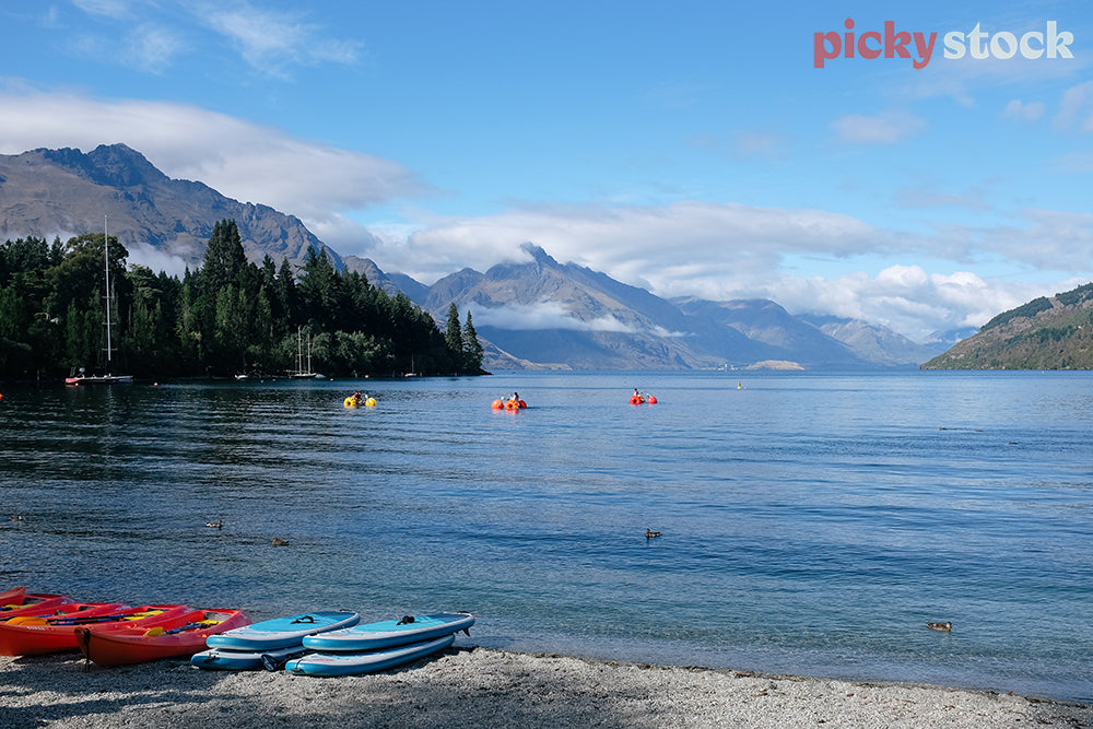 Looking at people in paddleboats on Lake Wakatipu with mountains in the distance