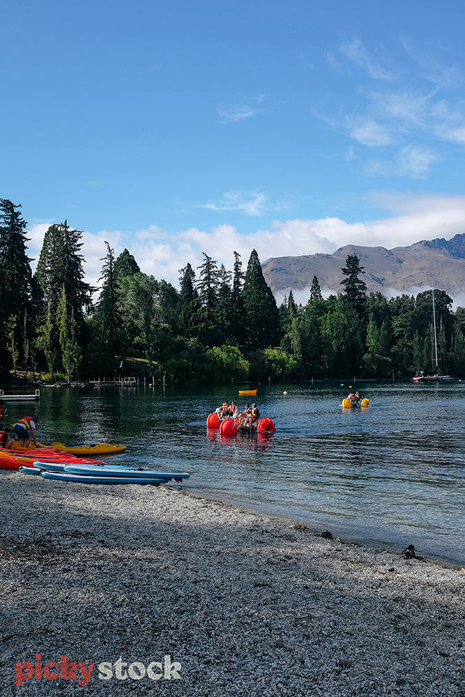 Looking at people in paddleboats on Lake Wakatipu with mountains in the distance.