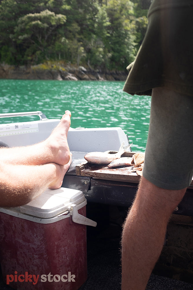 Person's legs relaxing on a small boat while fishing