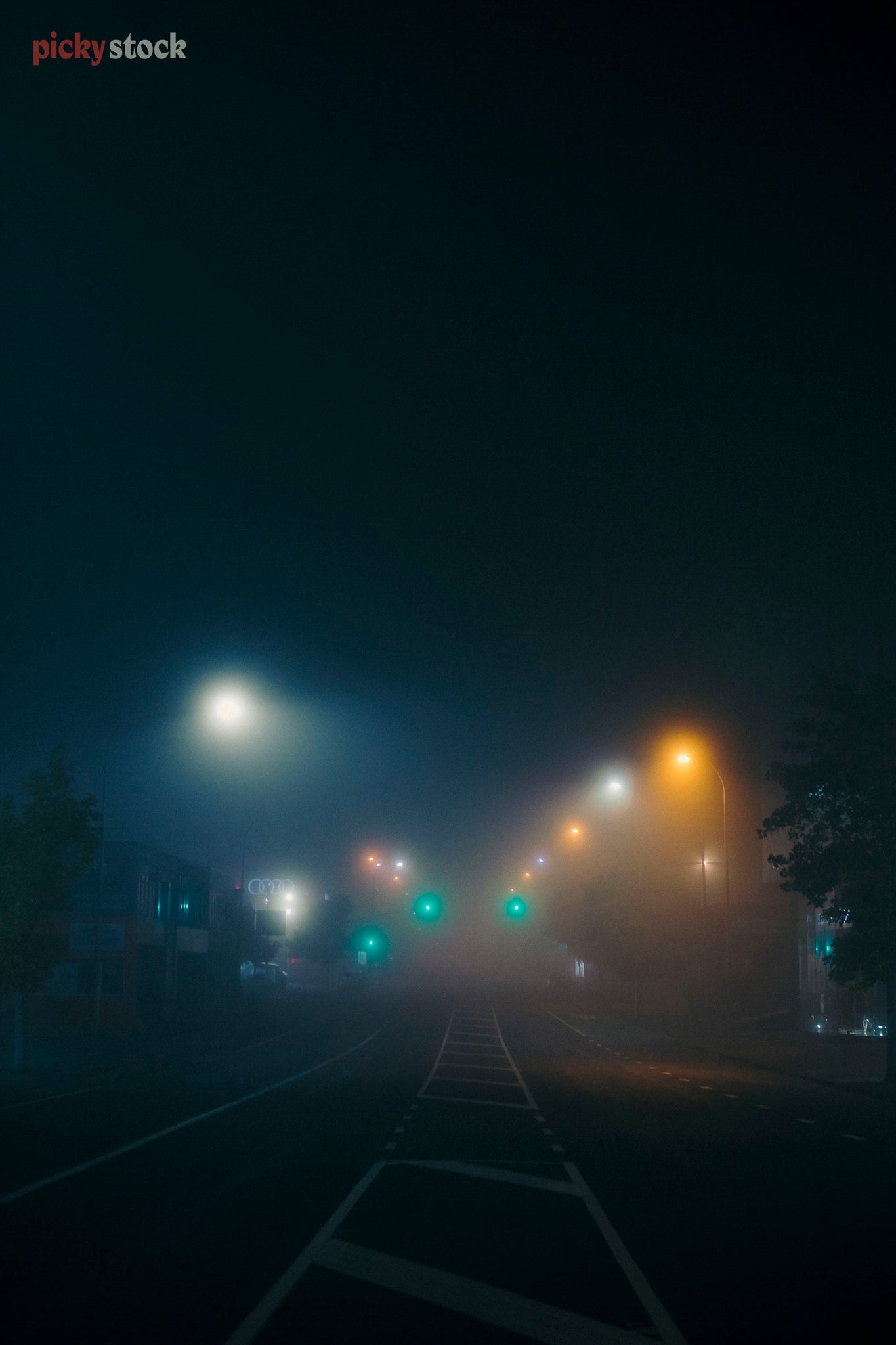Moody coloured traffic lights peek through the mist and haze early morning or late at night. 