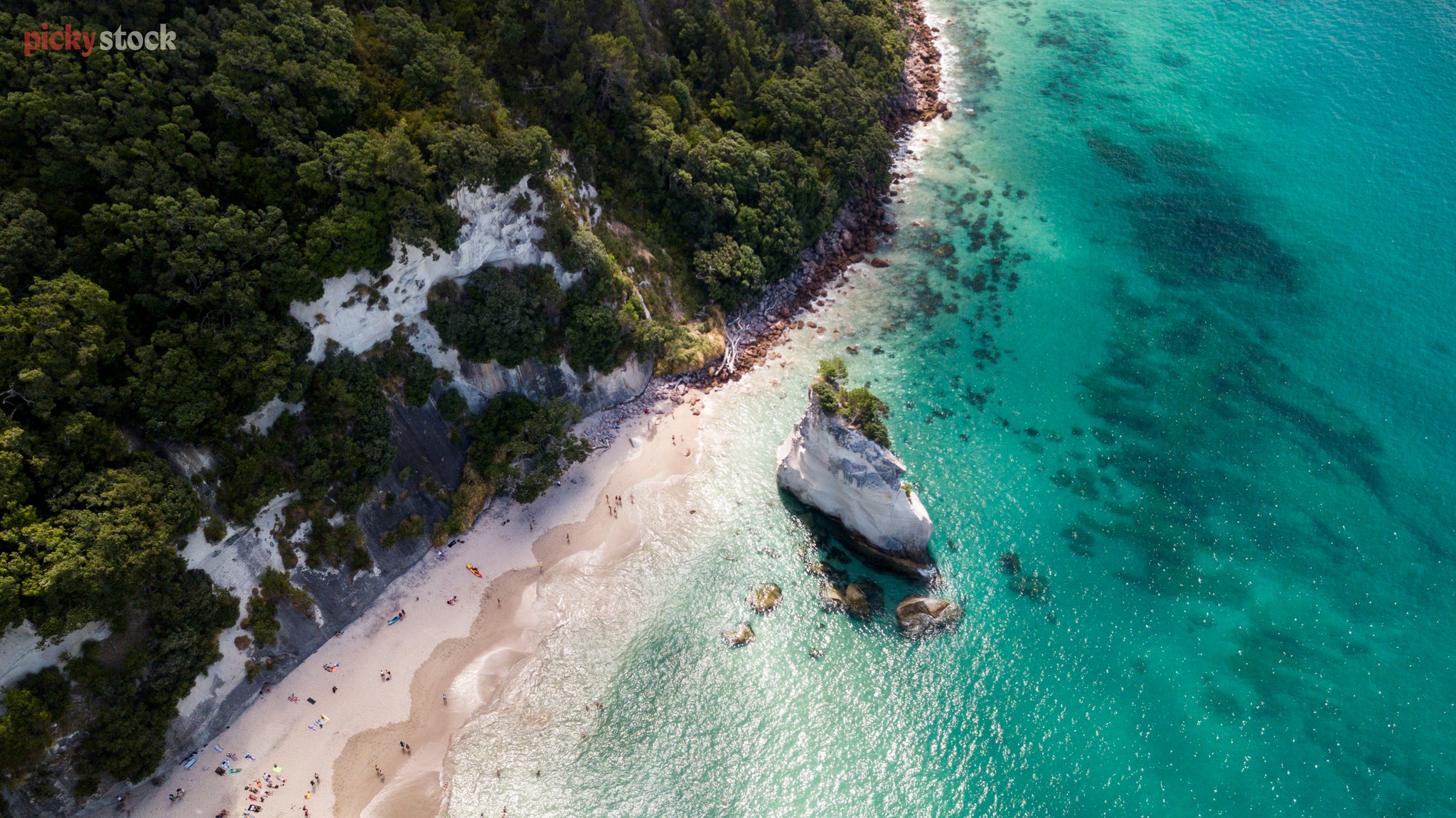 Aerial image of bright, crystal clear water as it hits the pristine sands and headland. 