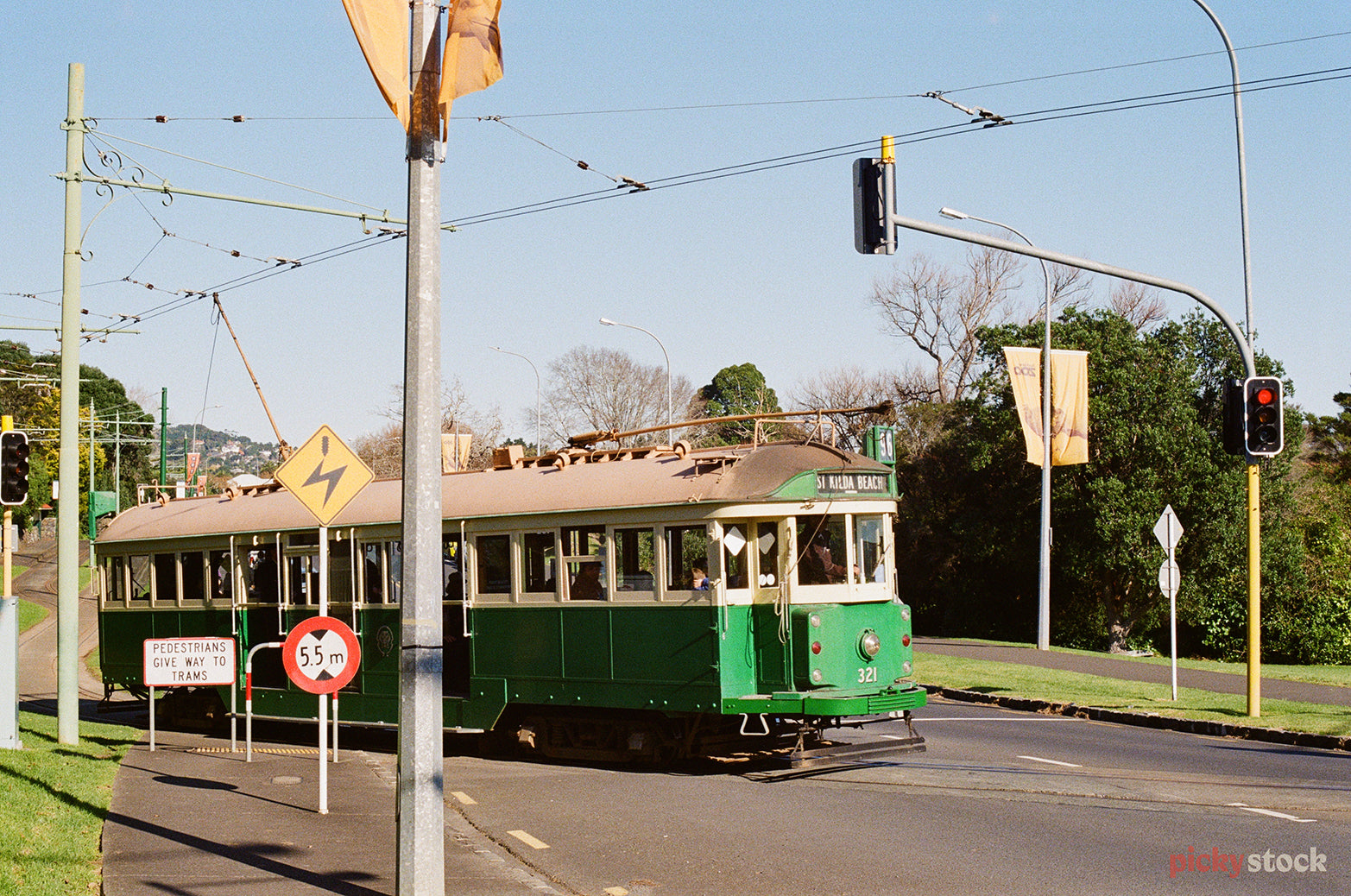 An old bright green tram turns across the tracks at Western Springs. The tram says "Saint Kilda" on the front of it. 