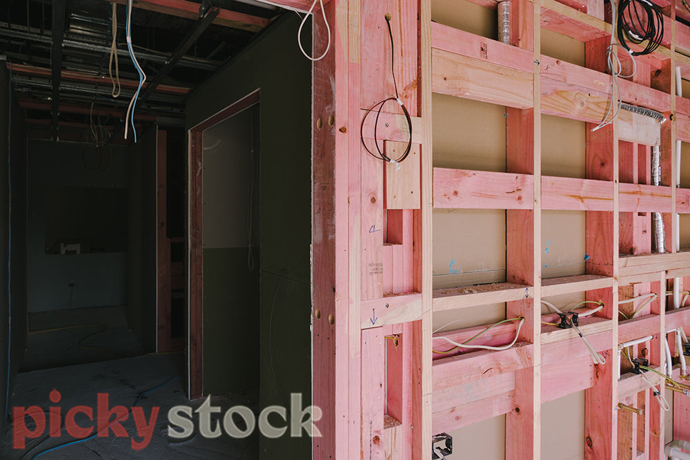 Internal pink exposed wall, in a home building site. Electrical wires visible.