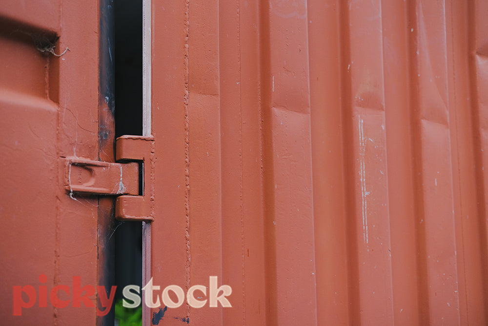 Close up of dinged rust-orange cargo container