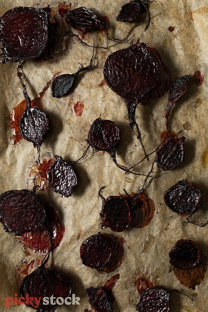 Roasted beetroot sitting on cooked brown baking paper. 