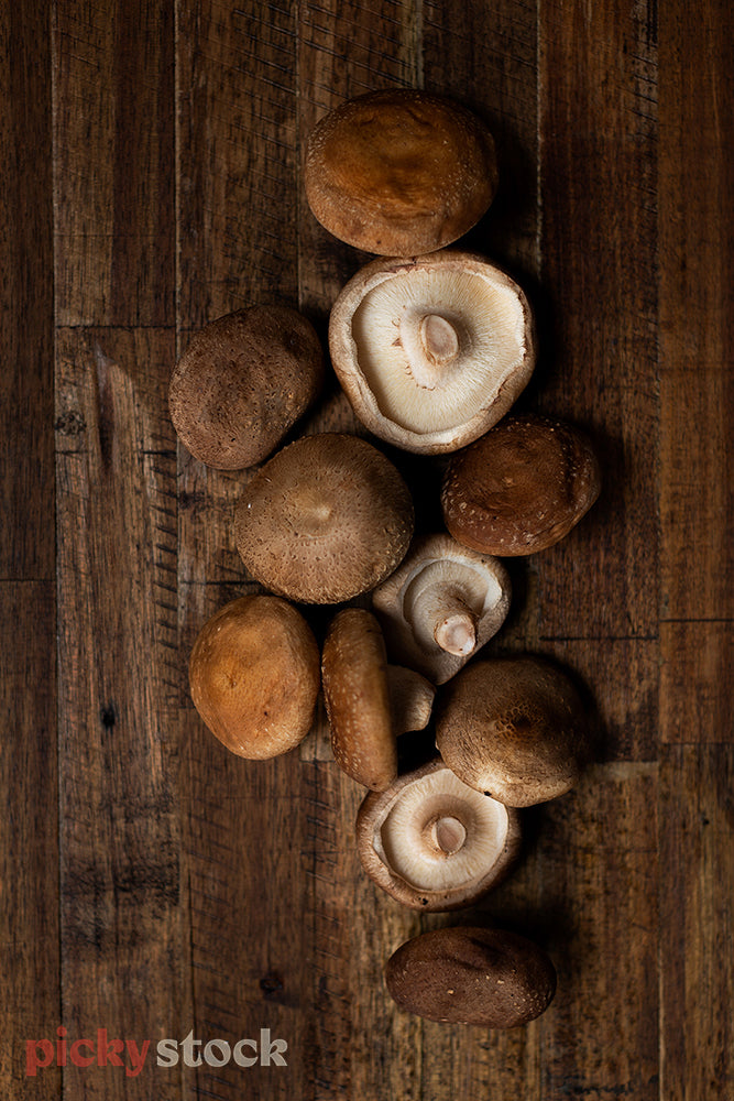 Mushrooms sitting on dark wooden chopping board. 