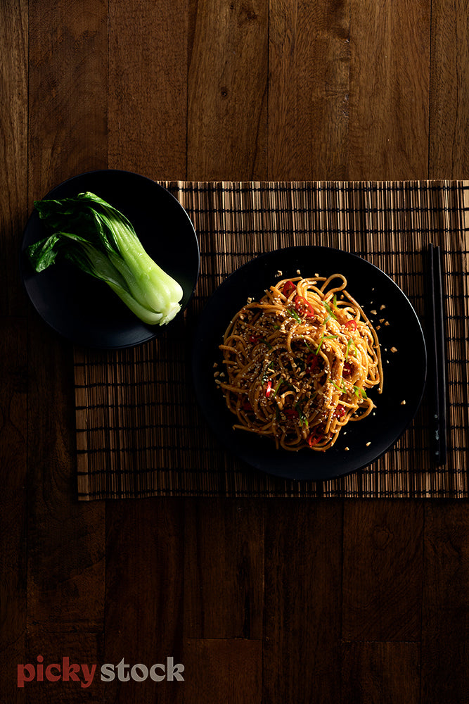 Bok choy and noodle dish on bamboo placemat. 